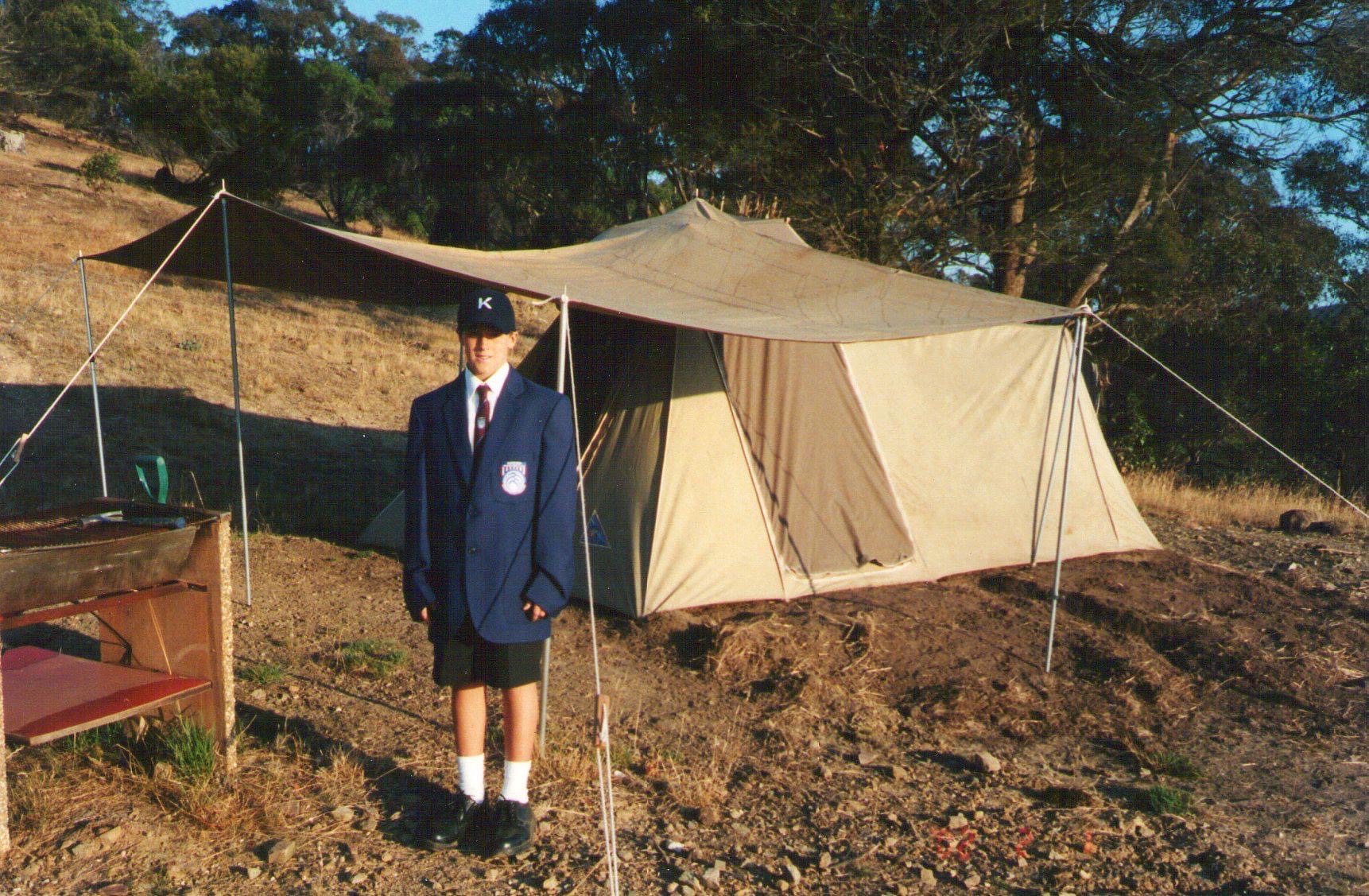 Hall Charter at age 12 in school uniform beside the tent he lived in